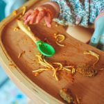 toddler's hand, a spoon and a messy table with food