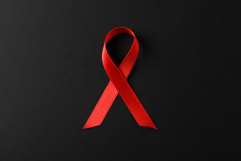 AIDS Awareness Red Ribbon On Black Background, Space For Text